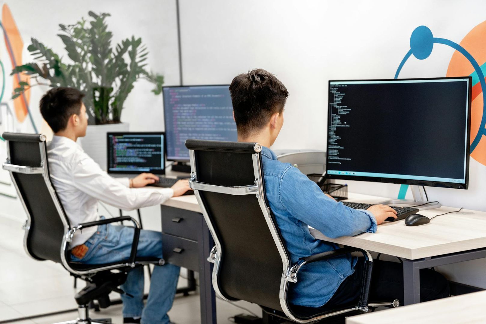 To personer koder ved datamaskiner, reflekterer et samarbeidende arbeidsmiljø.